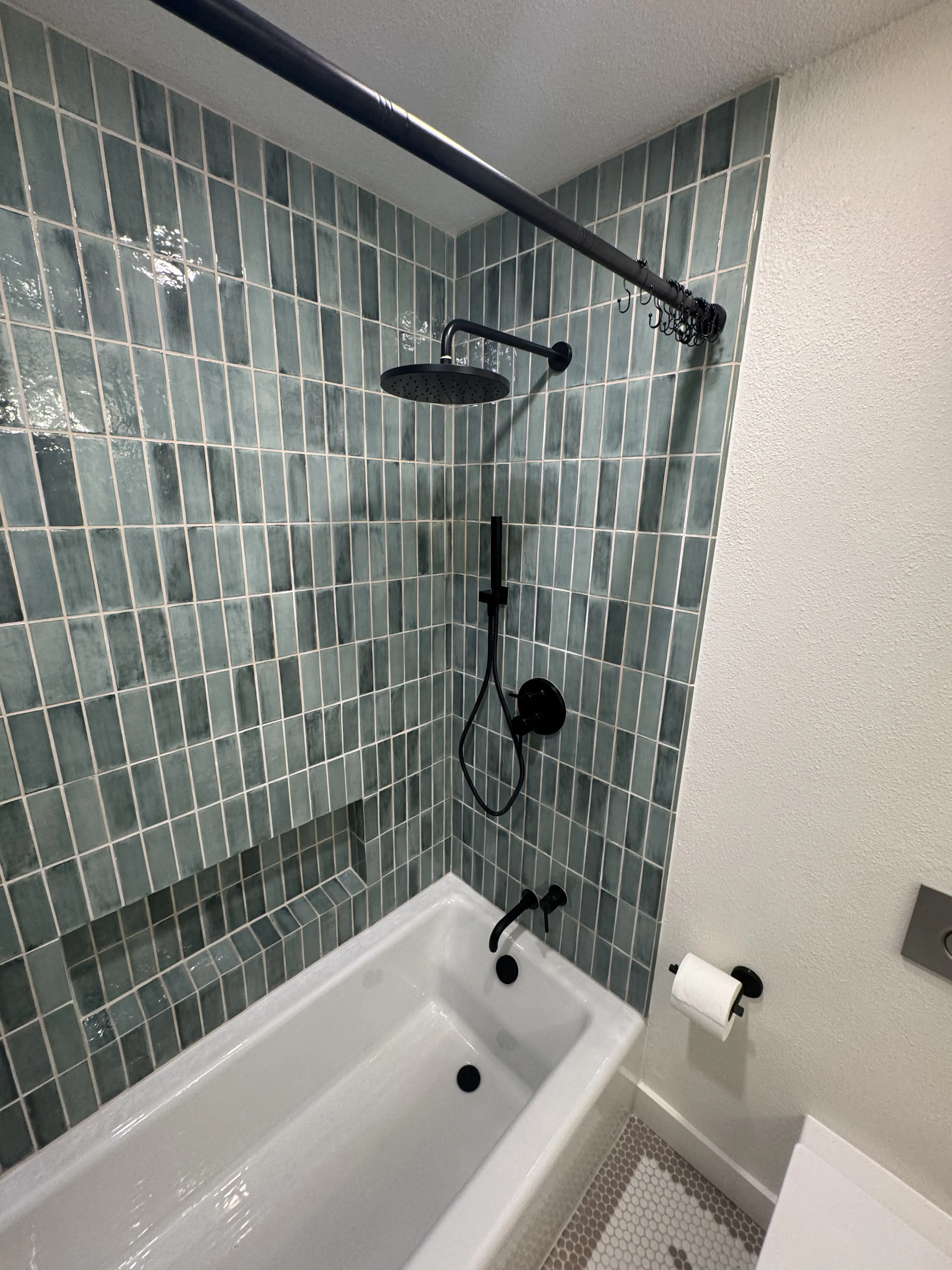 Green tile tub-shower surround with matte black fixtures — Bozeman bathroom remodel
