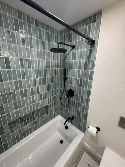 Green tile tub-shower surround with matte black fixtures — Bozeman bathroom remodel